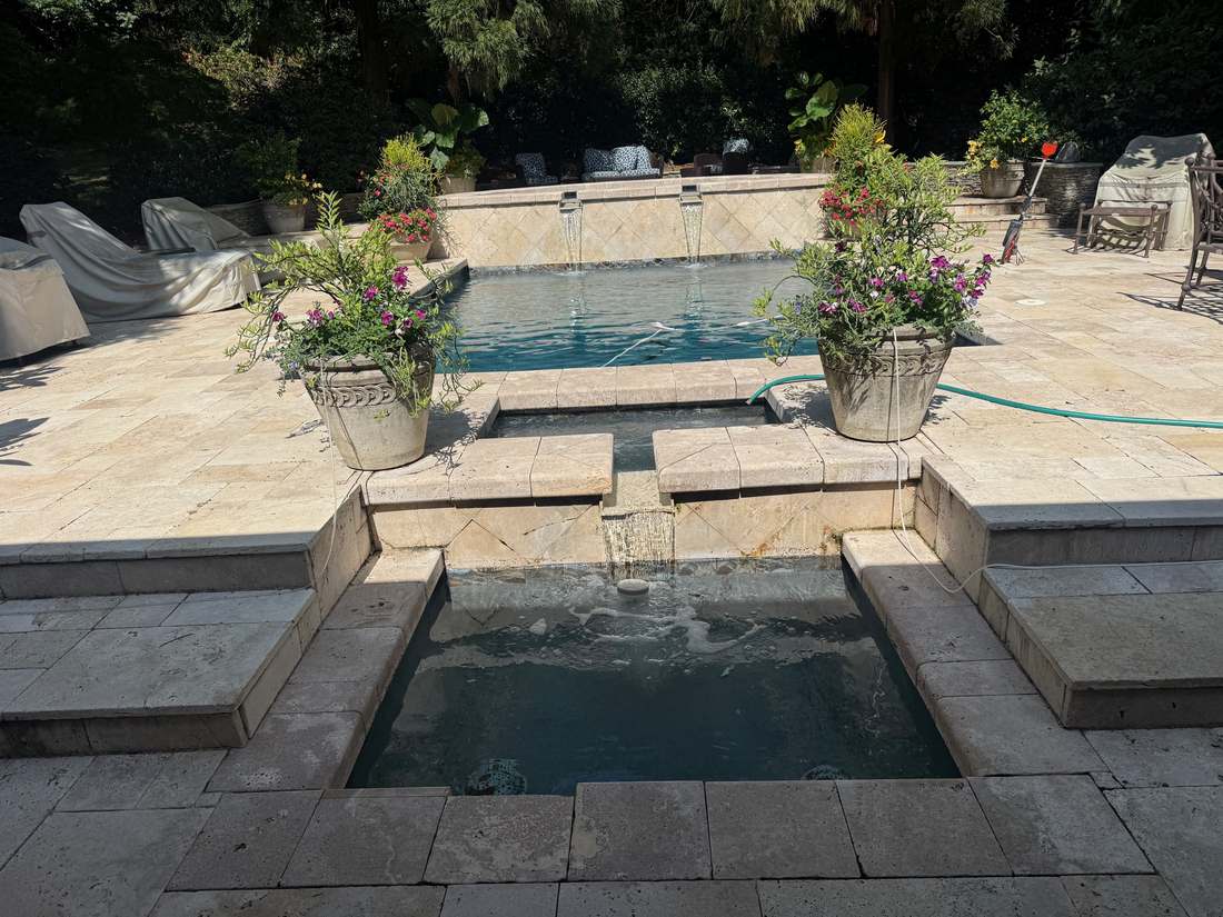 Tiered travertine spillway steps between spa and pool
